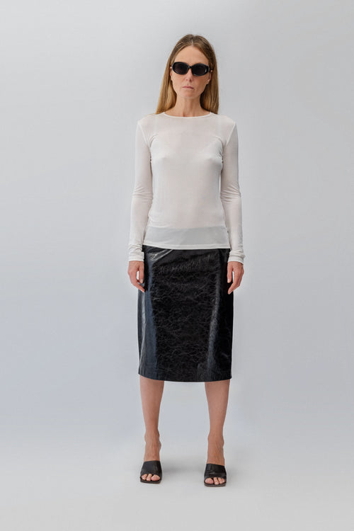 Shiny leather skirt by VICTORIA SLAVINSKAIA on model with a white long-sleeve silk top